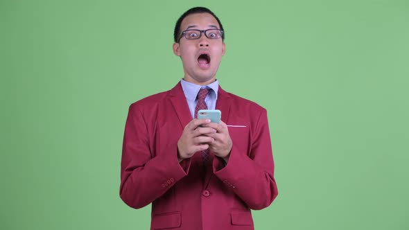 Happy Asian Businessman Using Phone and Getting Good News