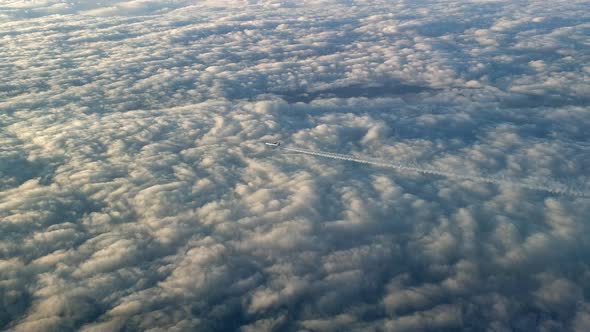 Incredible view from the cockpit of an airplane flying high above the clouds leaving a long white co