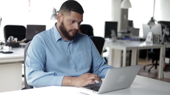 Serious Young Male Professional Using Laptop at Workplace