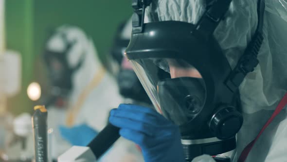 Researcher in a Hazmat Mask Is Looking Into the Microscope