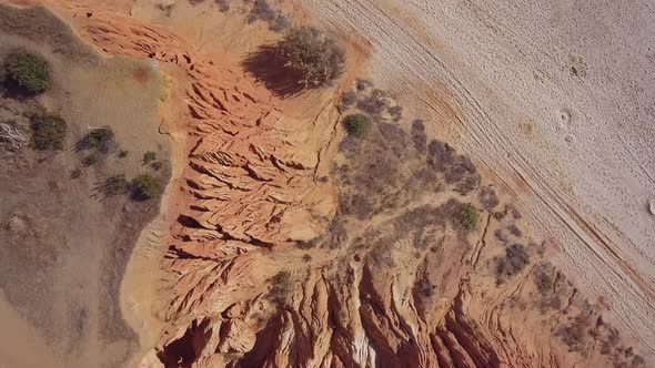 Aerial Footage of the Smooth Descent of Sandy Cliffs and Eroded Hills on the Portuguese Beach of