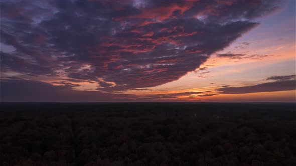 Orange to pink cloud sunset Timelapse above the forest , with sunlight, France