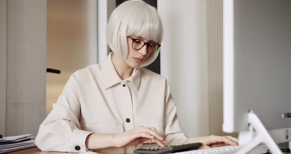 Woman Sit at Workplace Desk Working and Using Calculator Laptop Calculate Costs