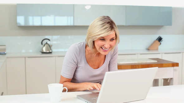 Blonde Woman Drinking Coffee While Using Laptop