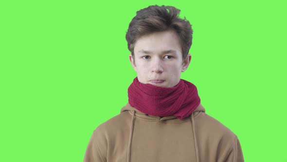 Portrait of Ill Boy Sneezing at Green Background. Close-up of Millennial Caucasian Teen in Red Scarf