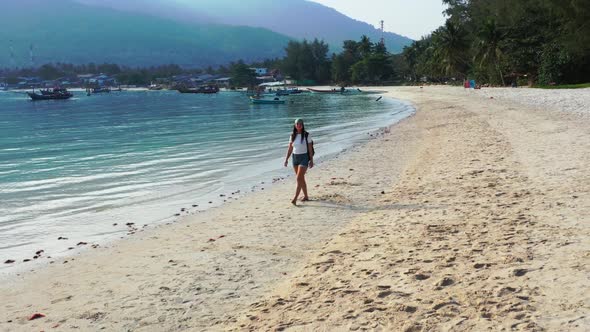 Beautiful women sunbathing on luxury shore beach vacation by aqua blue ocean and white sand backgrou