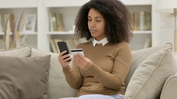 Online Shopping Success on Smartphone By Young African Woman on Sofa