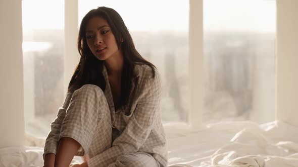 Asian Woman Sitting on a Bed at Home