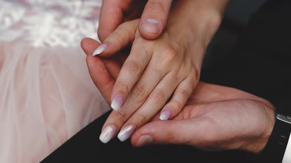 groom in suit holds hand of future wife sitting together