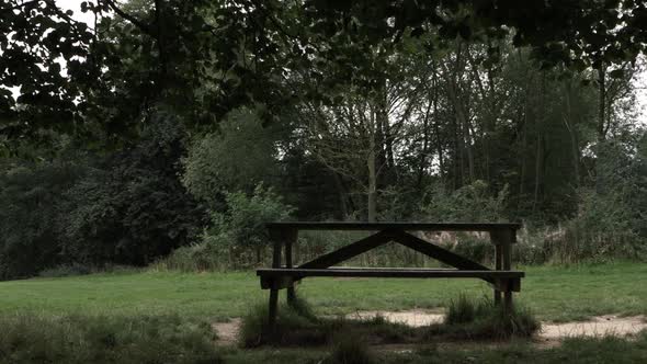 Wooden picnic bench in countryside park wide panning shot