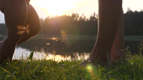 Baby and Mommy Practicing First Walks Barefoot on Grass at Sunlight. 