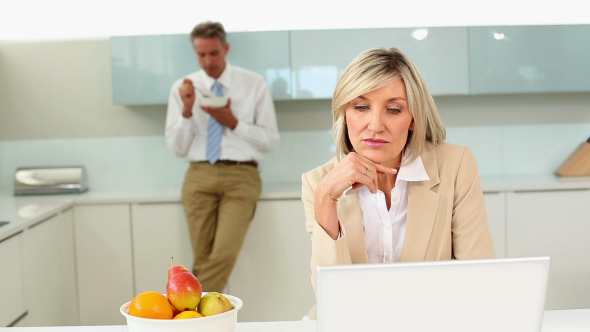 Businesswoman Using Laptop While Husband Eats