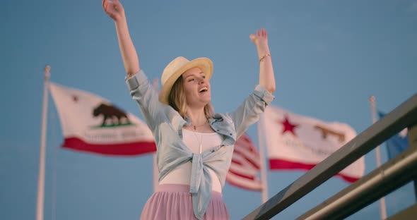 Happy Pretty Woman Is Dancing, California and American Flag Waving on Background