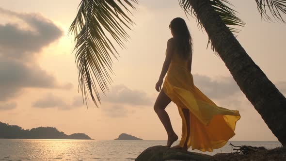 Young beautiful girl in yellow dress looking into the sea. Ocean.