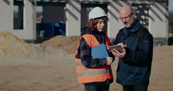 Concentrated Engineers Discussing Examining and Developing at Construction Site