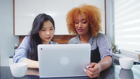 Multiracial Friendship. African American Black Asian Woman Working Browsing Social Media with Coffee