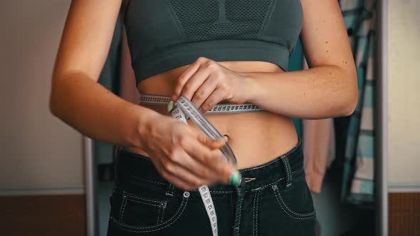 Girl with a Beautiful Figure Put On Old Big Jeans and Measures Her Waist