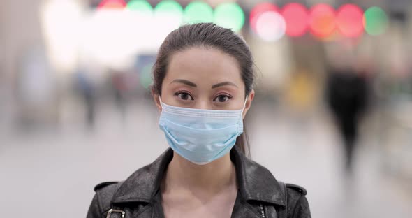 Chinese woman at train station in London wearing face mask to protect from co