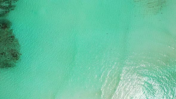 Aerial drone seascape of tranquil seashore beach holiday by turquoise ocean and white sand backgroun