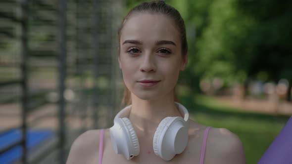 Portrait of the Yoga Woman Wearing a Headphones on Her Neck Looking at the Camera