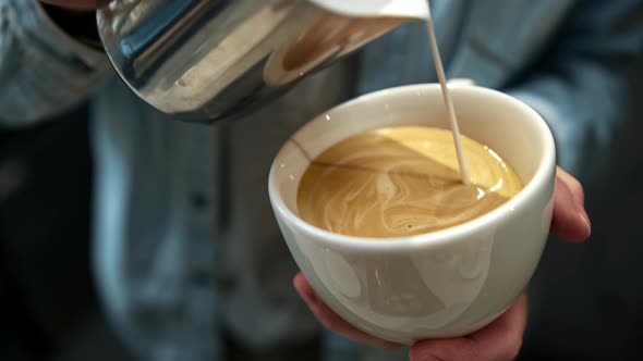 Barista steaming milk. barista whips milk in a pitcher with hot steam from coffee machine.