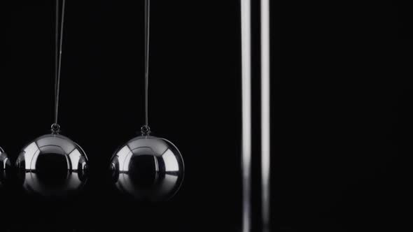 The balls of a Newtons Cradle colliding in slow motion