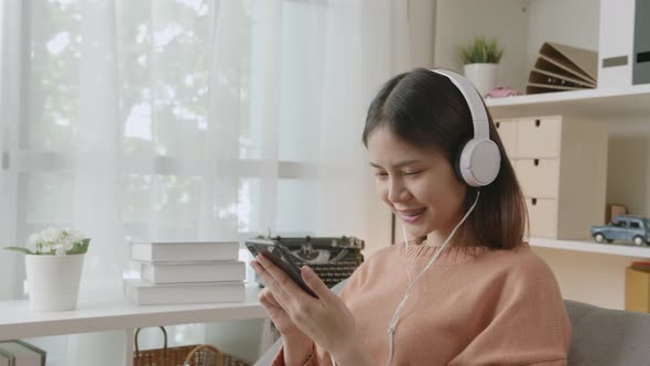 Woman of happy smiling are listening to music from white headphones and using smartphone