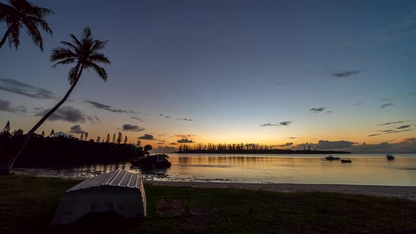 Small boats move with the current on a secret bay, Isle of Pines. Day to night timelapse.