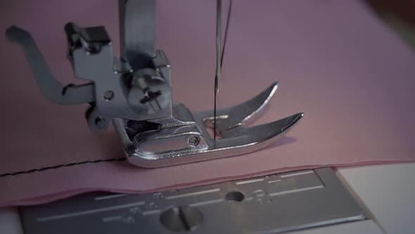 The needle of a sewing machine makes a thread stitch