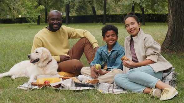 Portrait of Cheerful Afro Family with Dog on Picnic in Park