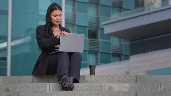 Young Hispanic Businesswoman Sitting Outdoors Working Remotely on Internet Typing on Laptop Overtime