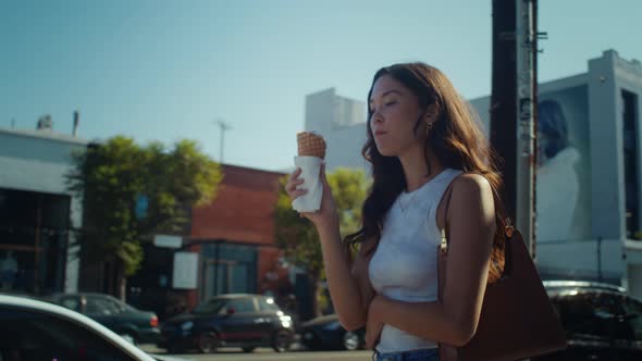 Attractive Girl Tasting Ice Cream Going Down Street