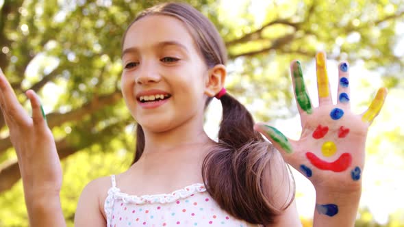 Happy girl with hands painted in water colors