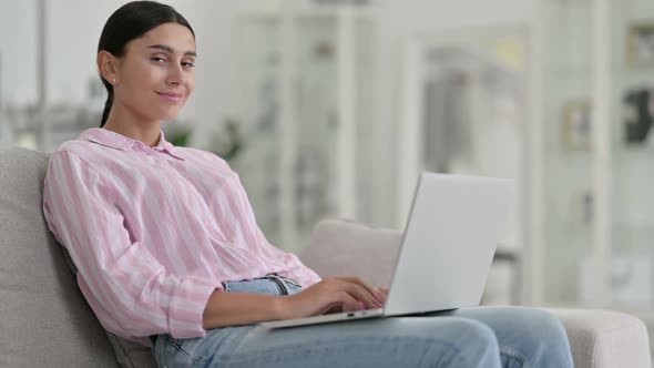 Young Latin Woman with Laptop Smiling at Camera at Home