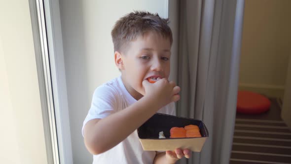 a Little Boy Eats Rolls Out of the Box