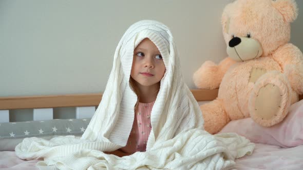 Happy Little Girl Plays After Sleep Hids Under Blanket in Bed and Smiles