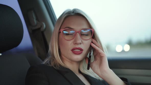 Blonde Talks with Smile on the Smartphone When Sits in the Car on Front Seat