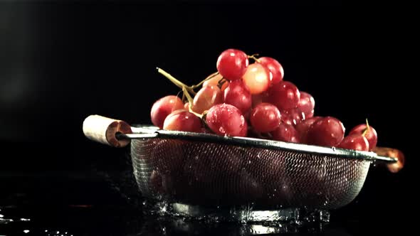 A Colander with Grapes Falls on the Table with Drops of Water