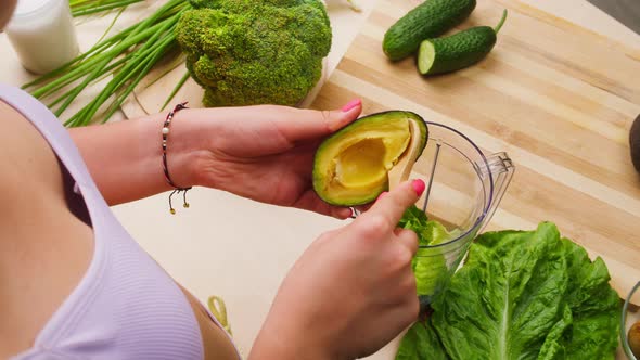 Woman Putting Avocado with Wood Spoon Into Blender Closeup Cooking Green Detox Smoothie in the