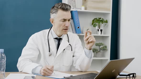 Doctor's appointment on the distance. Caucasian male doctor using laptop