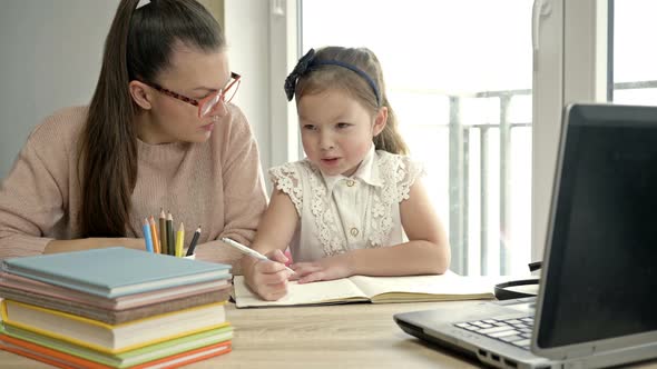 Mom Helps a Little Elementary School Student with Her Homework. Back To School.