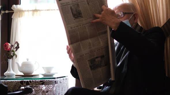 Old Grandfather Reads the Press While Sitting in a Cafe