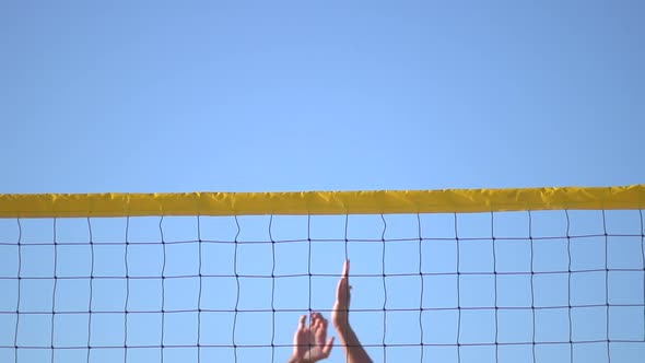 A man spiking a beach volleyball.