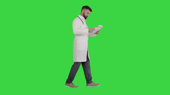 Male Doctor Walking and Looking at Cardiogram on a Green Screen, Chroma Key.