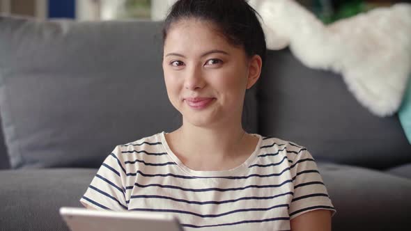 Portrait video of young Asian woman with tablet at home