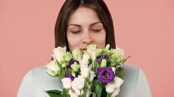 Beauty Portrait Closeup of Woman with No Makeup and Long Brown Hair Holding and Smelling Bunch of