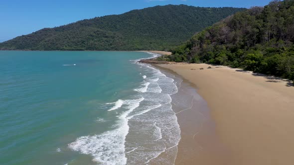 Cow Bay backward aerial over ocean waves, in Daintree Rainforest, Queensland, Australia