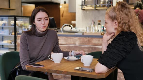 Two Beautiful Girls in a Restaurant at a Table Talking About Different Things