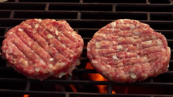 Two Raw Meat Burger Cutlet with Onions Are Grilling Above the Open Fire