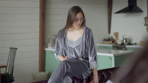 Portrait of Dissatisfied Young Asian Woman in Eyeglasses and Nightie Putting Away Business Graph